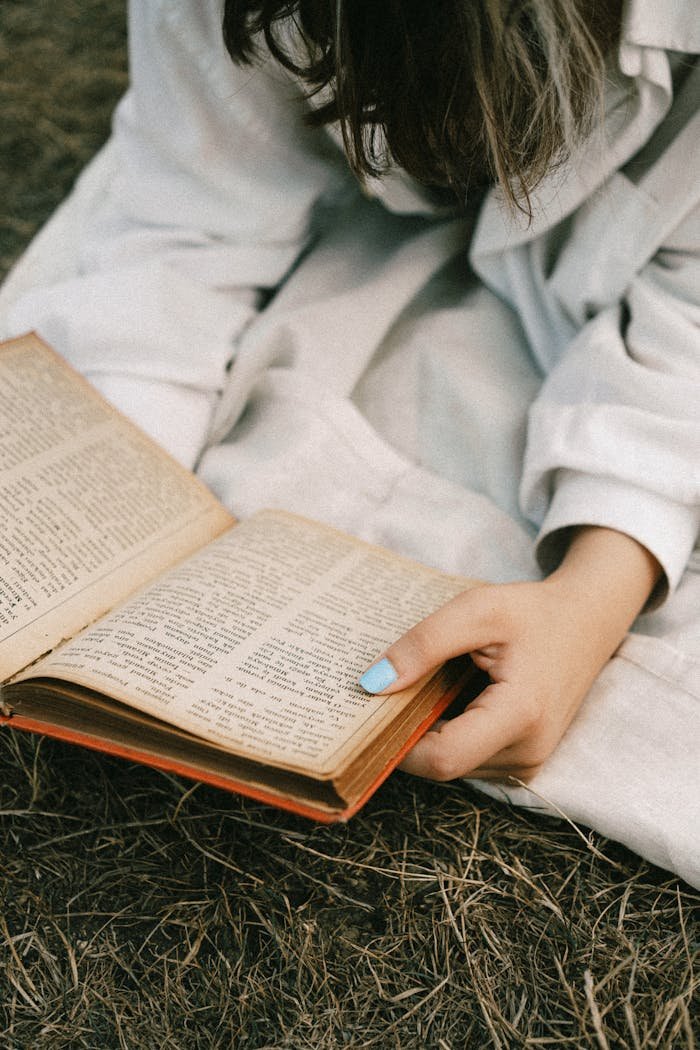 A woman reading an old book outdoors on a grassy field in İstanbul.